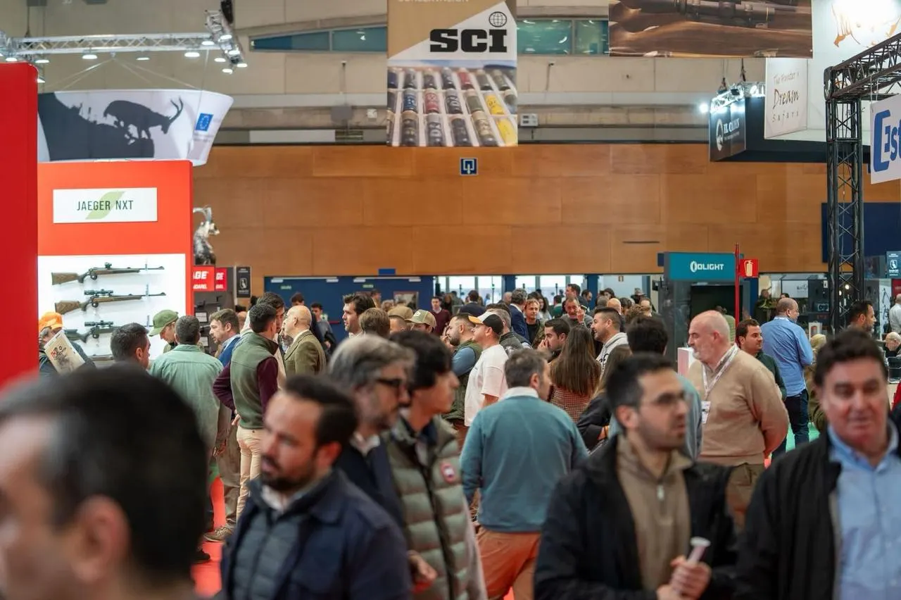 Visitors crowd the aisles of a hunting and conservation fair beneath an SCI banner.