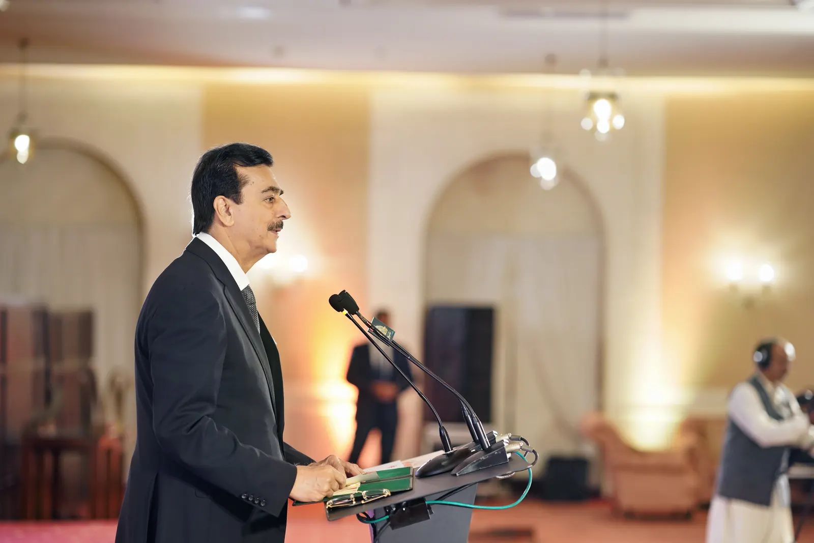 A guest of honour addresses the gala from the lectern beneath the ballroom arches.