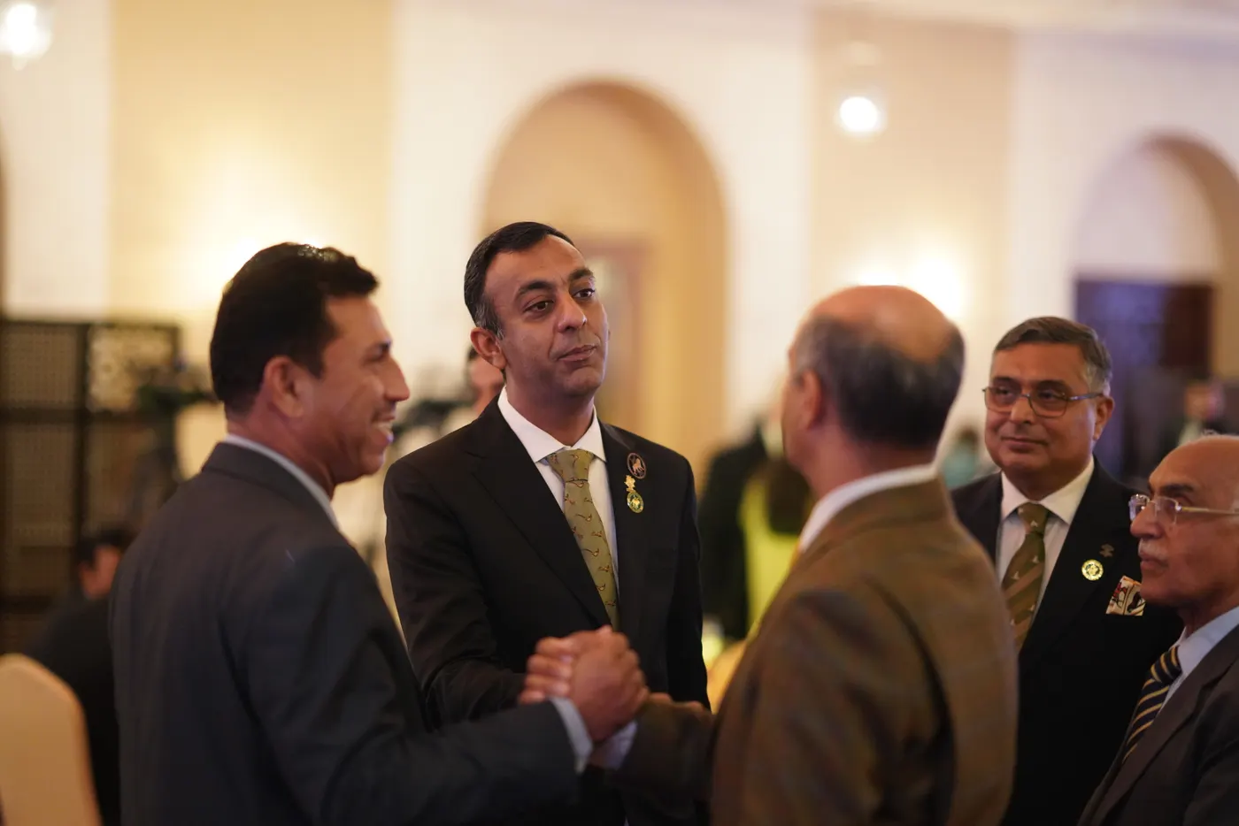 Members shake hands and share a laugh in the ballroom before the gala.
