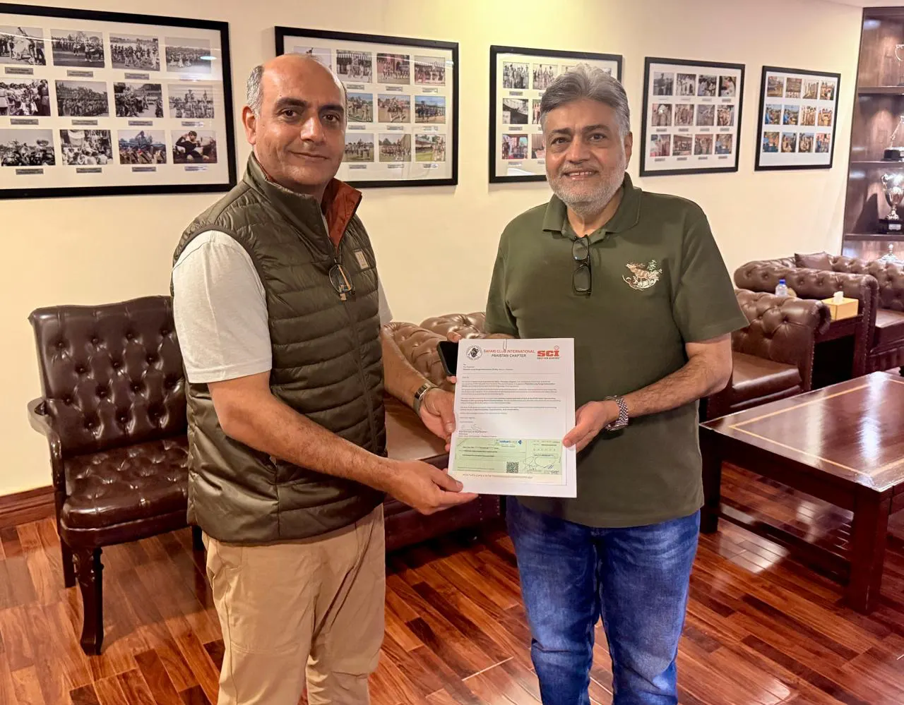 Two members hold a letter on Safari Club International Pakistan Chapter letterhead.
