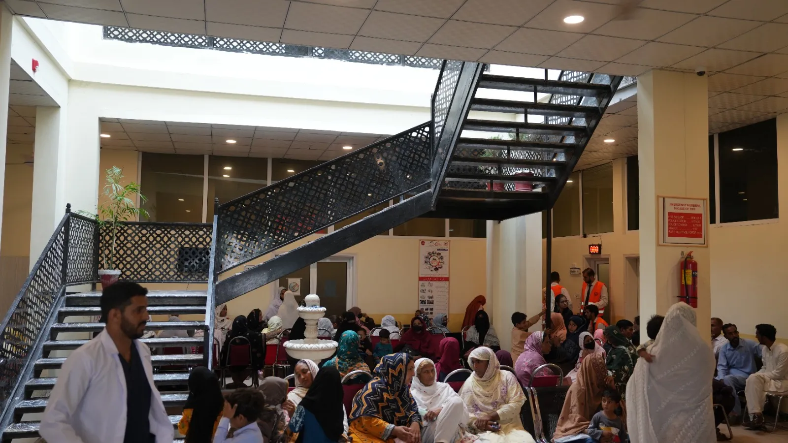 Patients wait in the camp’s atrium beneath a steel staircase.