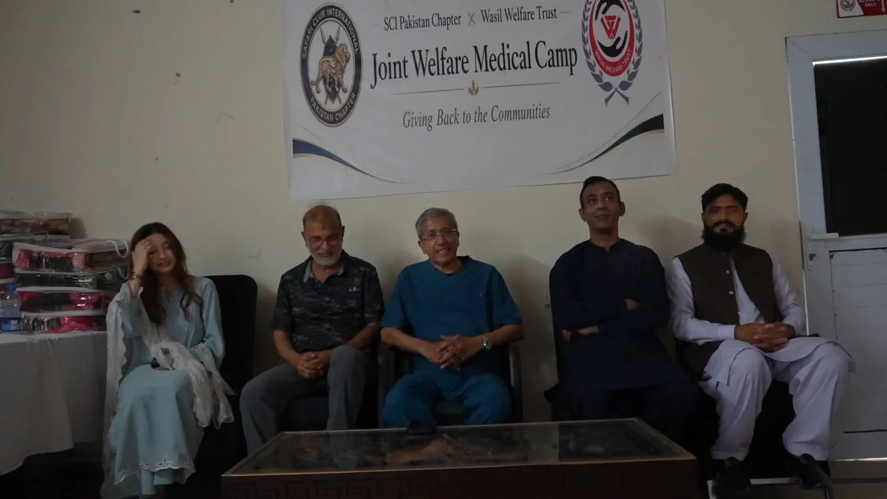 Representatives and members sit beneath the Joint Welfare Medical Camp banner with blankets stacked beside them.